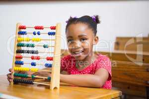 Smiling pupil using abacus in classroom