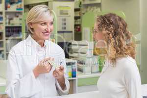 Pharmacist showing blister packs to costumer