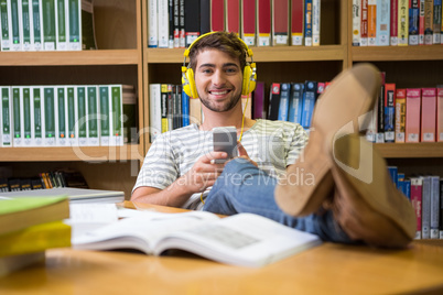 Student listening music in the library with smartphone