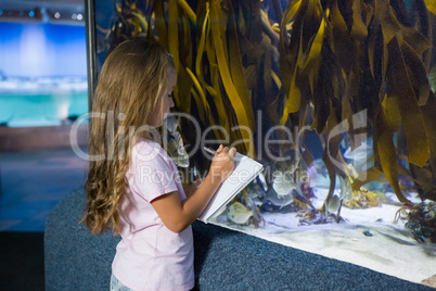 Cute girl looking at fish tank