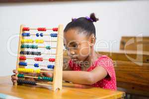 Cute pupil using abacus in classroom