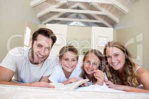 Happy family on the bed reading book