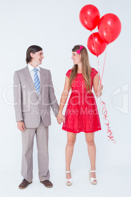 Smiling geeky couple standing hand in hand