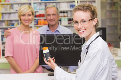 Pharmacist showing medicine jar to a customer
