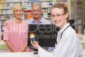 Pharmacist showing medicine jar to a customer