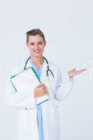 Doctor holding clipboard and presenting with her hand
