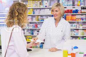 Customer handing a prescription to a smiling pharmacist