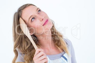 Thoughtful woman holding wooden spatula
