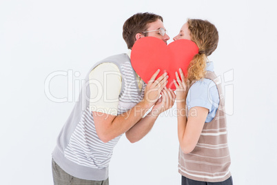 Geeky hipster couple kissing behind heart card