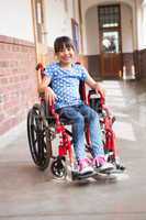 Cute disabled pupil smiling at camera in hall