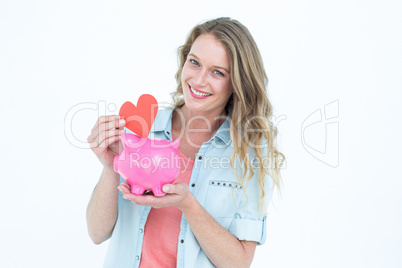 Smiling woman holding piggy bank and red heart