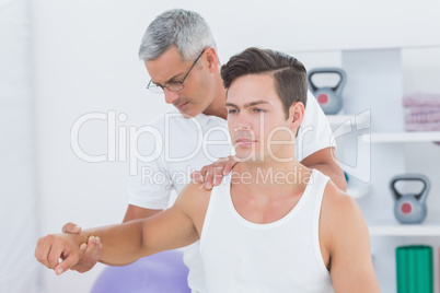 Doctor stretching a young man arm