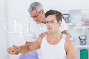 Doctor stretching a young man arm