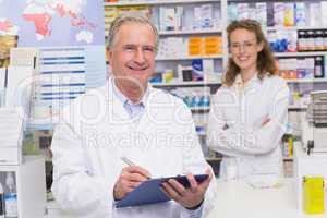 Senior pharmacist writing on clipboard