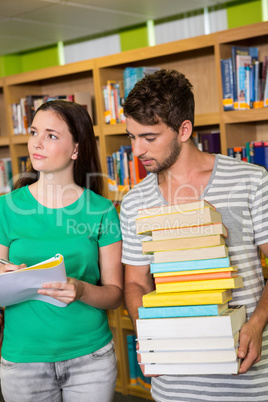 Students with pile of books in the library