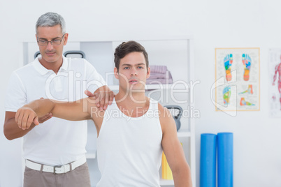 Doctor stretching a young man arm