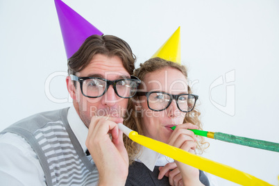 Geeky hipster couple blowing party horn