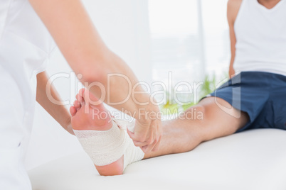 Doctor bandaging her patient ankle