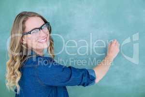 Smiling geeky teacher writing on blackboard