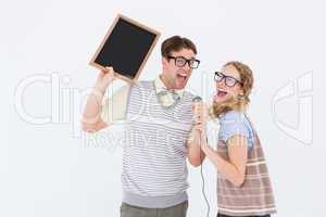 Geeky hipster couple singing into a microphone