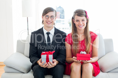 Cute geeky couple smiling and holding gift