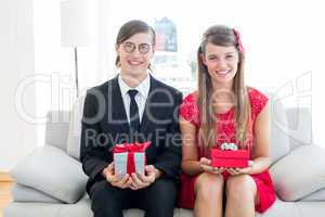 Cute geeky couple smiling and holding gift
