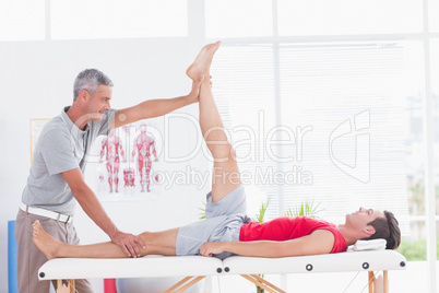 Physiotherapist doing leg stretching to his patient