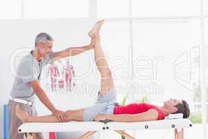 Physiotherapist doing leg stretching to his patient