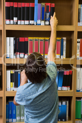 Student picking a book from shelf in library