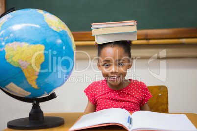 Cute pupil holding books on her head