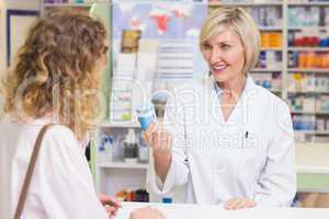 Pharmacist showing medicine jar to costumer