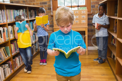 Cute pupils reading books at library