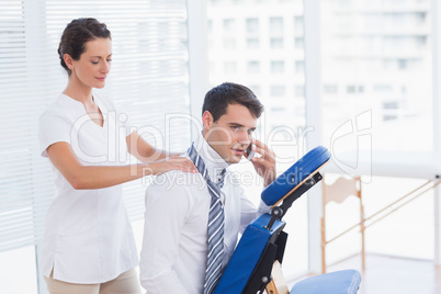 Businessman having back massage while talking on the phone