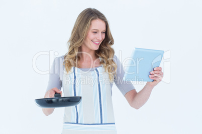 Smiling woman holding frying pan and tablet pc