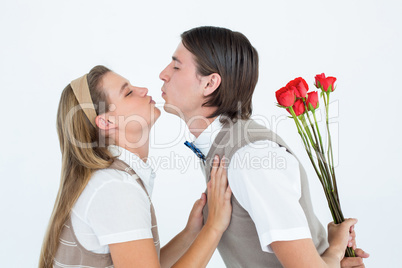 Geeky hipster holding roses and giving a kiss to his girlfriend