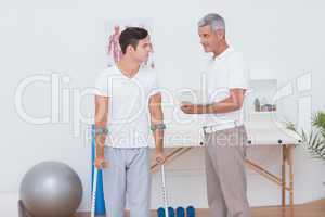 Man with crutch speaking with his doctor