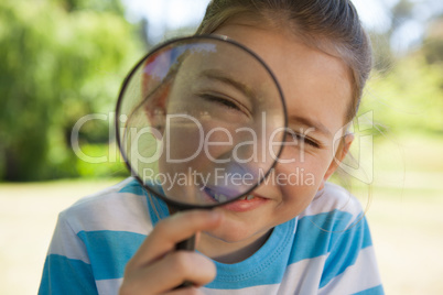 Cute little girl looking through magnifying glass