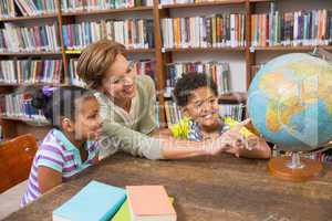 Pupils and teacher looking at globe in library