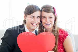 Cute geeky couple smiling and holding heart