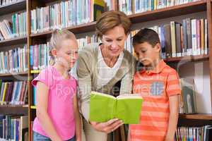Teacher reading book with pupils at library