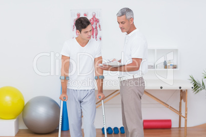 Doctor showing clipboard to his patient with crutch