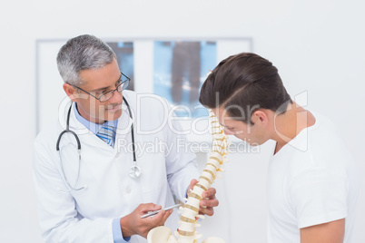 Doctor explaining anatomical spine to his patient Doctor explaining anatomical spine to his patient