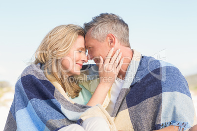 Happy couple wrapped up in blanket