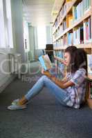 Student sitting on floor in library reading