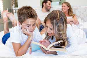 Happy family on the bed reading book