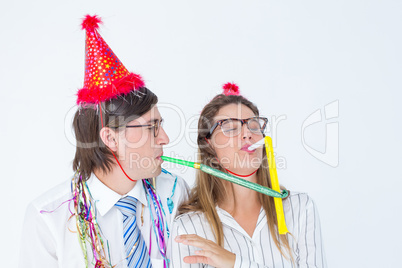 Geeky hipster wearing a party hat with blowing party horn