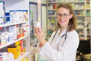 Smiling pharmacist taking jar from shelf
