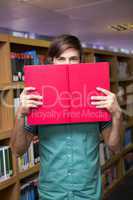 Student covering face with book in library