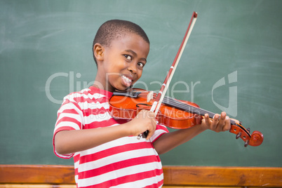 Happy pupil playing violin in classroom