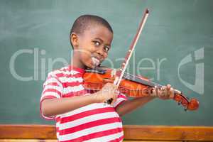 Happy pupil playing violin in classroom